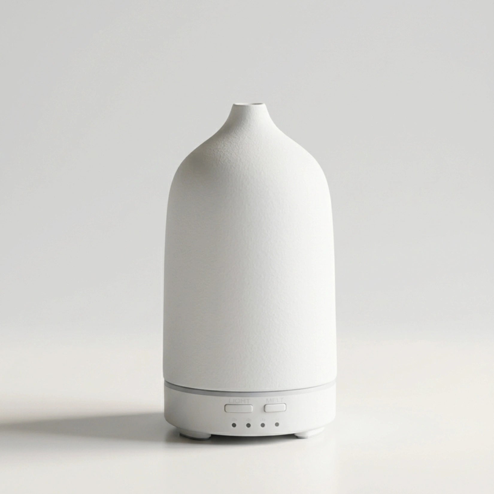 A minimalist white diffuser with a textured matte finish and a sleek cylindrical base, shown against a clean light gray studio background.