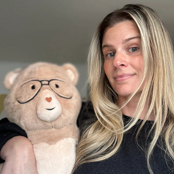Woman holding a weighted bear with glasses indoors